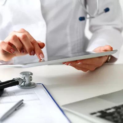 Arts leest artikel over vrijstelling vennootschapsbelasting voor zorginstellen op tablet
