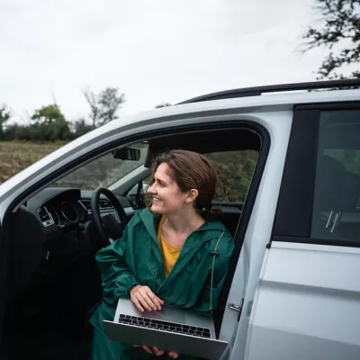 Ondernemer zit in auto met laptop op schoot