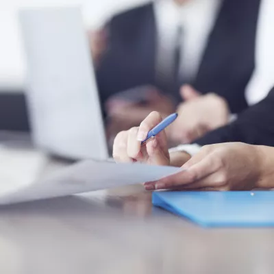 Iemand houdt blauwe pen vast boven papieren