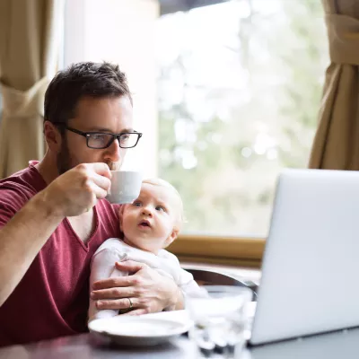 Man met kind op schoot achter laptop